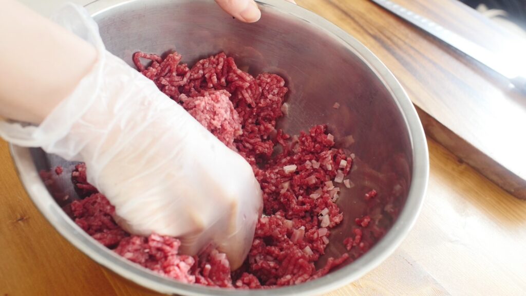 ベーコンを加えた合いひき肉に塩を入れてよく混ぜる