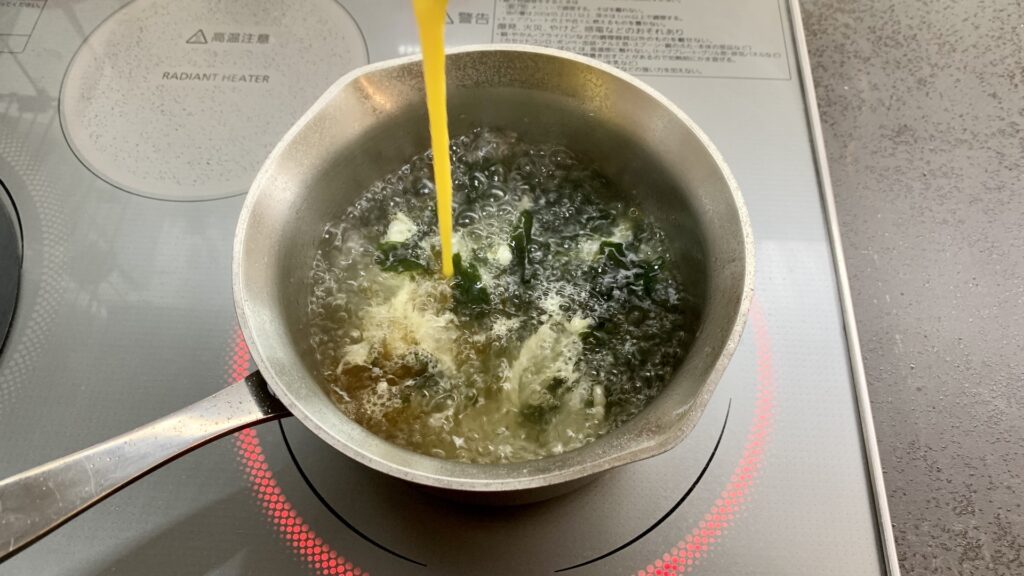 沸騰しているスープに卵を加える