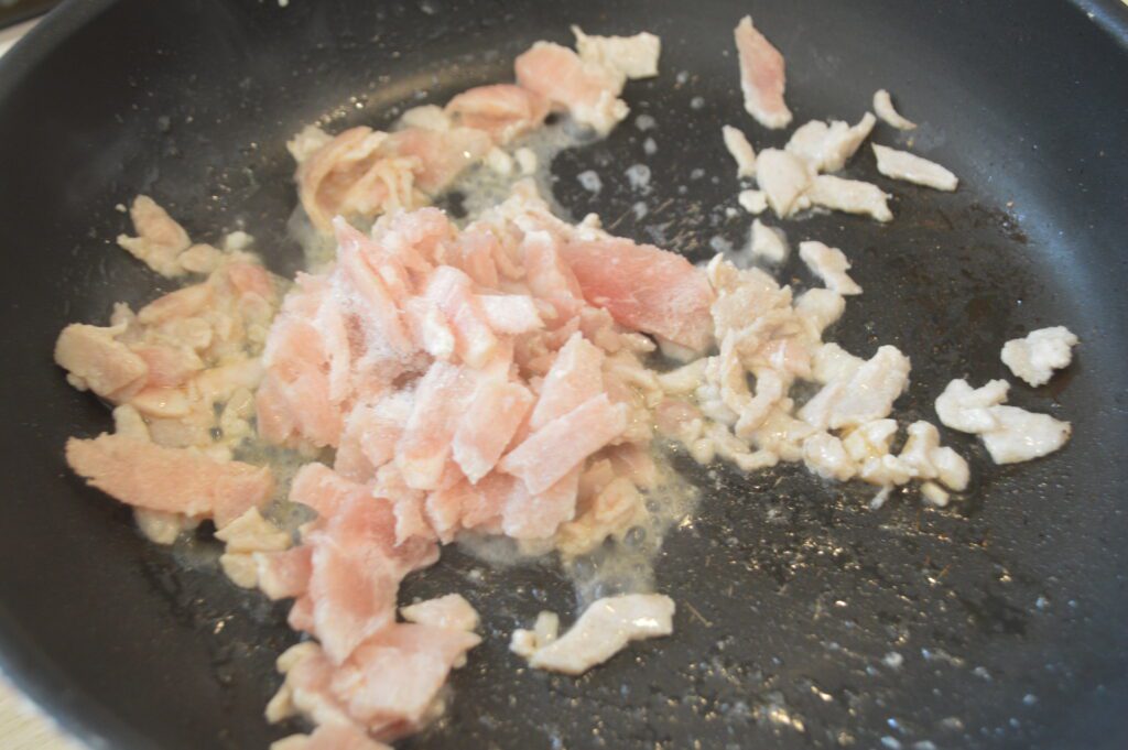 フライパンにごま油を熱し、豚肉を炒めます。